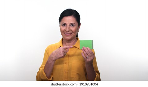 Cheerful Old Lady Holding Small Green Box In Hand And Pointing With Her Finger, Isolated On White Background. Creative People Can Put The Product They Want In The Woman's Hand.