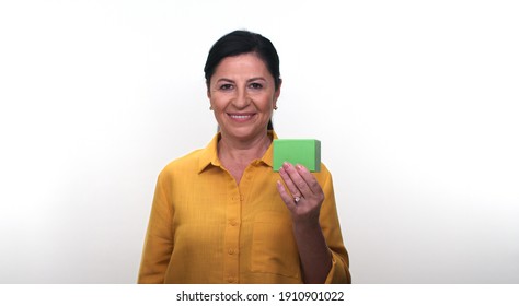 Cheerful Old Lady Holding Small Green Box In Hand And Pointing With Her Finger, Isolated On White Background. Creative People Can Put The Product They Want In The Woman's Hand.