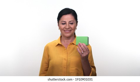 Cheerful Old Lady Holding Small Green Box In Hand And Pointing With Her Finger, Isolated On White Background. Creative People Can Put The Product They Want In The Woman's Hand.