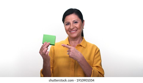 Cheerful Old Lady Holding Small Green Box In Hand And Pointing With Her Finger, Isolated On White Background. Creative People Can Put The Product They Want In The Woman's Hand.