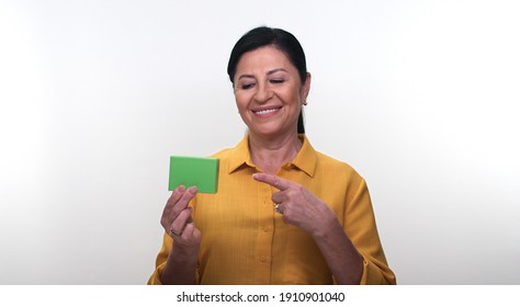 Cheerful Old Lady Holding Small Green Box In Hand And Pointing With Her Finger, Isolated On White Background. Creative People Can Put The Product They Want In The Woman's Hand.