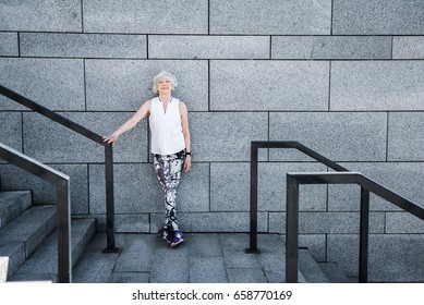 Cheerful Old Lady Relaxing After Exercise On Granitical Stairs Outdoors