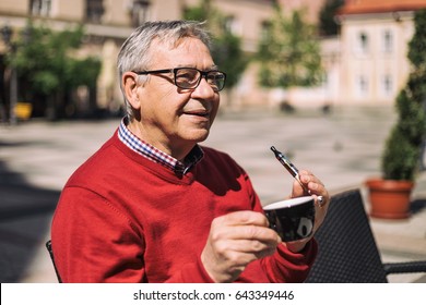 Cheerful Older Man Enjoys Drinking Coffee And Smoking E- Cigarette At The Bar.Senior Man Using Electronic Cigarette
Image Is Intentionally Toned.