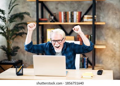 Cheerful Older Man In Smart Casual Wear And Eyeglasses Is Looking At Laptop Screen And Holding Hands Up In Winner Sign