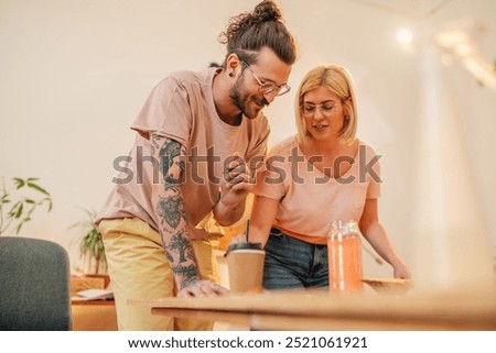 Cheerful painter couple standing at creative art studio and painting together. Portrait of a young artistic hipster couple at atelier with paintbrushes in hands creating unique artwork together.