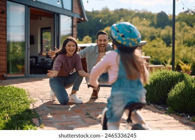 Cheerful parents encouraging their daughter in riding bicycle outdoors. - Powered by Shutterstock