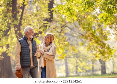 Cheerful pensioners enjoy their life walking together in the park and talking. Activities for elderly people - Powered by Shutterstock