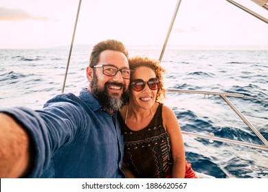 Cheerful people happy adult caucasian couple take selfie picture and enjoy together summer holiday vacation sailing with boat with ocean and sky in background - tourists lifestyle and fun in ocean