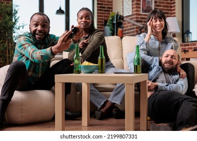 Cheerful People Having Fun Playing Video Games Strategy At House Party With Bottles Of Beer And Snacks. Group Of Friends Celebrating Hangout Reunion While They Play Game On Tv Console.