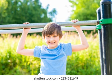 cheerful perky boy plays on uneven bars in the summer in the park - Shutterstock ID 2234311649