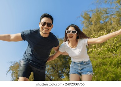 Cheerful and playful asian couple lover is taking selfie photo with bright sky. - Powered by Shutterstock