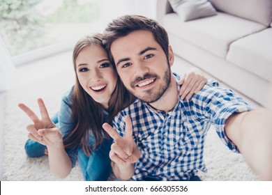 Cheerful playful sister and brother are taking selfie and showing peace signs. They are at home indoors, in casual outfits. They both have beaming smiles - Shutterstock ID 666305536