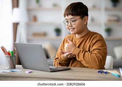 Cheerful Plump Chinese Boy Teenager Sitting In Front Of Laptop, Having Online Lesson, Showing Thumb Up At Computer Screen And Smiling, Thankful For Educational Course, Home Interior, Copy Space