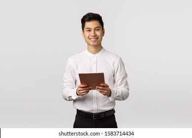 Cheerful, Polite Handsome Elegant Asian Guy In White Shirt, Black Pants, Holding Digital Tablet And Smiling Camera, Using Gadget For Work, Messaging Using Device, Shopping Online, White Background