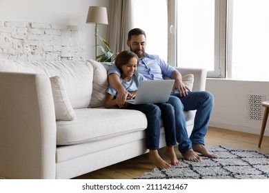 Cheerful Positive Dad And Happy Pre Teen Gen Z Son Using Shopping App On Laptop Computer On Comfortable Couch, Making Order, Watching Movie, Series Online, Making Video Call, Smiling At Display