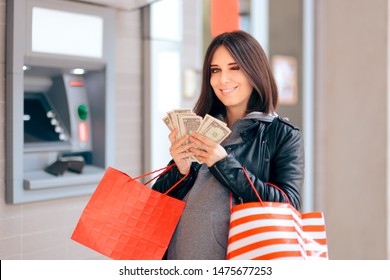 Cheerful Pregnant Woman Holding Money At The ATM. Woman Buying Baby Stuff With Cash Maternity Allowance 
