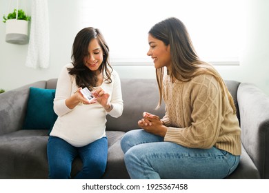 Cheerful pregnant woman and smiling midwife looking at the print ultrasound of a caucasian pregnant woman while sitting on the sofa