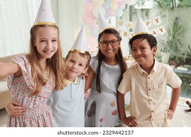 Cheerful preteen girl taking selfie with friends at birthday party - Powered by Shutterstock