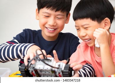 Cheerful Preteen / Teenage Asian Brother Assembles And Shows His Robotics Project To Cute Little Boy. Two Brothers Laugh, Smile, Have Fun. Family Activity, Quality Happy Time, Brotherhood Bonding.