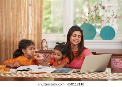 Cheerful Pretty Indian Woman Working On Laptop When Babysitting