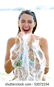 Cheerful Pretty Woman Splashin Water On Her Face In The Sea, Laughing.