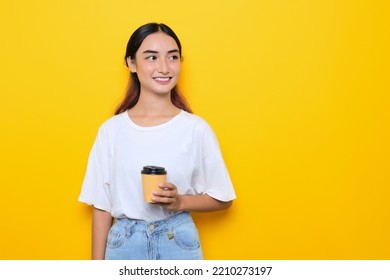 Cheerful pretty young girl in white t-shirt holding coffee cup and looking away at blank space isolated on yellow background - Powered by Shutterstock