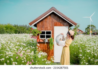 Cheerful Pretty Young Woman With Hair Tied By Handkerchief Standing And Holding Carry Box Of Her Lovely Prairie Dog Pet In Beautiful Flower Field Country Farm With Blue Sky.