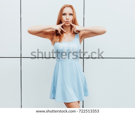 A cheerful red-haired beauty girl is having fun outdoors in a trendy blue summer dress. Outdoor.