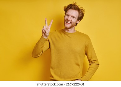 Cheerful Redhead Man Gesturing Welcome Sign While Standing Against Yellow Background