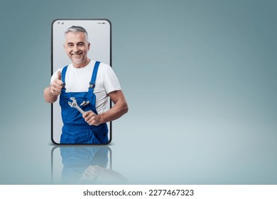 Cheerful repairman and plumber giving a thumbs up in a smartphone videocall and smiling, online  service concept - Powered by Shutterstock