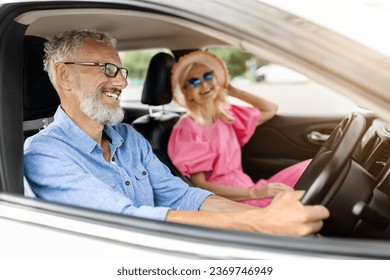 Cheerful retired man and woman travelling together by auto, enjoying road and have conversation. Happy senior couple friends have car ride, spending vacation or weekend together - Powered by Shutterstock