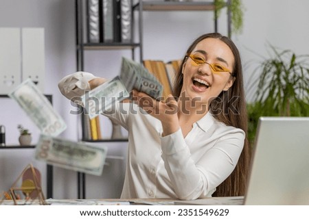 Cheerful rich young Caucasian business woman working on laptop and wasting throwing money to camera more tips earnings big profit success win lottery shopping. Happy freelancer girl at office desk