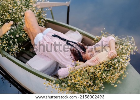 Cheerful romantic girl in a hat is riding boat. Summer mood lifestyle. Rest on the water on the river lake. Woman enjoying the weekend. Vacation in the countryside. Happy positive aesthetics emotions