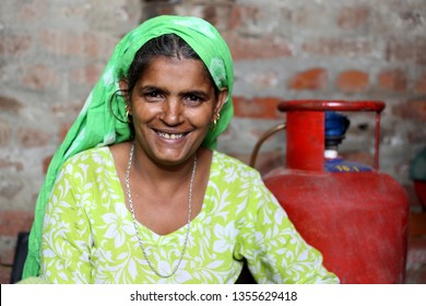 Cheerful rural women of Indian ethnicity sitting portrait at home near brick wall.