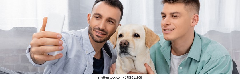 Cheerful Same Sex Couple Smiling And Taking Selfie With Labrador, Banner