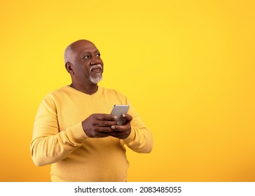 Cheerful senior African American man using mobile phone with new application, looking at empty space on orange studio background. Gadgets and mobile communication concept - Powered by Shutterstock