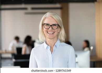 Cheerful Senior Businesswoman In Glasses Looking At Camera, Happy Older Team Leader Ceo Manager, Female Aged Teacher Professor Or Mature Executive Woman Mentor Smiling In Office Head Shot Portrait