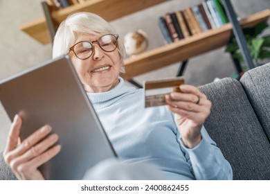 Cheerful senior caucasian woman using digital tablet and credit card for shopping online. E-commerce, e-banking, bank account debt, mortgage, pension receiving. Cashless payment - Powered by Shutterstock