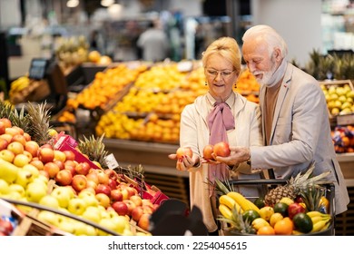 Cheerful senior couple is choosing apples at the supermarket. - Powered by Shutterstock