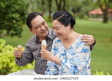 Cheerful senior couple eating ice-cream when enjoying romantic date in park - Powered by Shutterstock