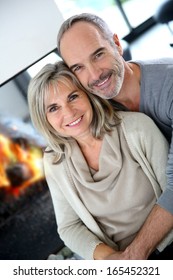Cheerful senior couple enjoying fireplace in winter