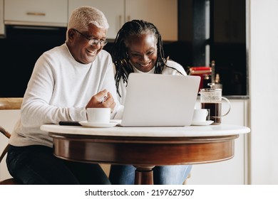 Cheerful senior couple having a video call on a laptop at home. Mature couple having a virtual meeting with a retirement consultant. Happy senior couple planning their retirement together. - Powered by Shutterstock
