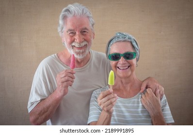 Cheerful Senior Couple Holding A Colored Popsicle Stick Looking At Camera, Happy Retirees Enjoying Retirement Eating A Fresh Popsicle