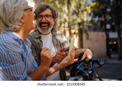 A cheerful senior couple is out in the city enjoying their retirement days and are using a smartphone together. - Powered by Shutterstock