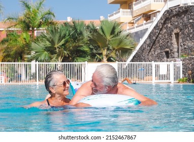 Cheerful Senior Couple Smile In The Swimming Pool Floating On Inflatable Mattress. Happy Relaxed Retired Couple Enjoying Summer Vacation