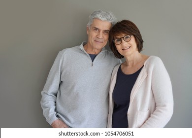 Cheerful senior couple standing on grey background