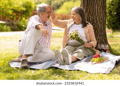 Cheerful senior european man gives bouquet of flowers to woman, enjoy picnic together in park, outdoor. Couple celebrate birthday, anniversary and holiday, romantic date, lifestyle and weekend - Powered by Shutterstock