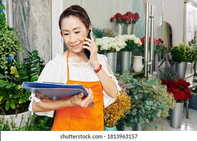 Cheerful Senior Female Florist Talking On Phone And Ordering Flowers And Wrapping Paper