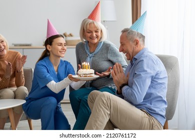 Cheerful senior friends active beautiful man and women celebrating birthday at retirement home, wearing colorful hats, positive nurse holding birthday cake with lit candles in front of birthday man - Powered by Shutterstock