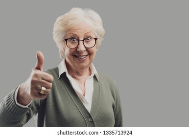 Cheerful senior lady giving a thumbs up and smiling at camera, approval and achievement concept